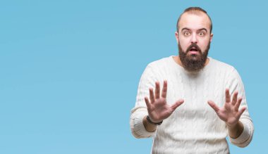 Üzerinde kış kazak giyen genç beyaz hipster adam arka plan korkuyor ve korku ifade dur hareketi el ile ile dehşete şokta bağırarak izole. Panik kavramı.