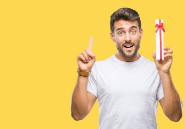 Sevgililer veren aşık genç yakışıklı adam izole arka bir fikirle sürpriz üzerinde mevcut veya gülen yüz, bir numara ile işaret parmağı soru