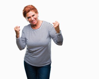 Gülümseyen ve başarı için çığlık Atrractive üst düzey beyaz Kızıl saçlı kadın izole arka plan çok mutlu ve heyecanlı kaldırdı, silah ile kazanan jest yapıyor. Kutlama kavramı.