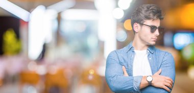 İkna ve kendine güvenen genç yakışıklı adam tarafına silahlarla seyir gülümseyen izole arka plan üzerinde güneş gözlüğü takıyor geçti