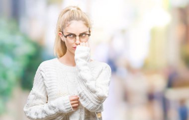 Stresli ve gergin elle çivi ısırma ağzına bakarak izole arka plan üzerinde gözlük takan genç güzel sarışın bir kadın. Anksiyete sorunu.