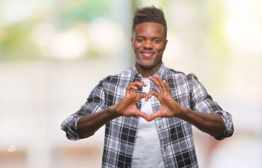 Afrikalı-Amerikalı genç aşık kalp simgesi ve elleriyle şekil gösteren gülümseyen izole arka plan üzerinde. Romantik kavramı.