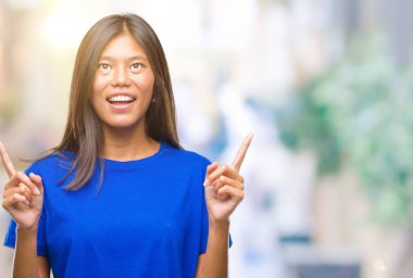 Genç Asyalı kadın izole arka plan üzerinden hayran ve yukarıya bakıp parmakları ile işaret şaşırttı ve silah kaldırdı.