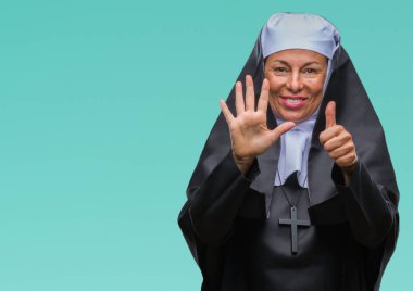 Orta yaş üst düzey Hıristiyan Katolik Rahibe kadın gösterilen ve parmakları ile işaret izole arka plan yüzünden kendinden emin ve mutlu gülümseyerek süre 6 numara.