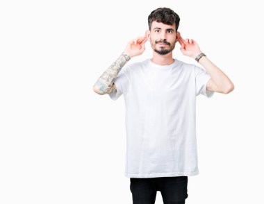 Üzerinde beyaz t-shirt giyen genç yakışıklı adam arka plan gülen çekerek kulakları parmaklar, komik jest ile izole. Seçmelere sorun