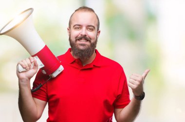 Beyaz delikanlı işaret ve başparmak kadar mutlu yüz gülümseyen tarafı ile gösteren izole arka plan üzerinde megafon ile bağırarak