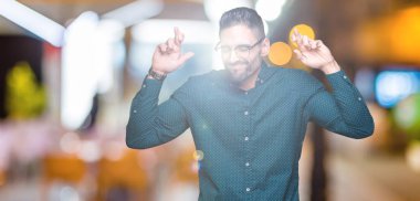 Umut ve gözleri kapalı geçiş parmaklarıyla gülümseyen izole arka plan üzerinde gözlük takan genç yakışıklı iş adamı. Şans ve batıl kavramı.