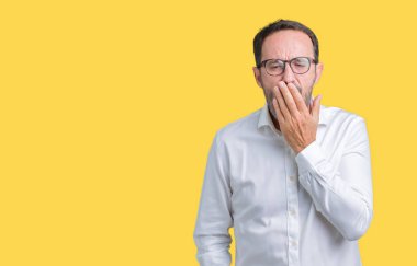 Yakışıklı orta yaş esneme izole arka plan üzerinde gözlüklü zarif üst düzey iş adamı sıkılmış kapsayan ağız el ile yorgun. Restless ve uyku hali.