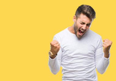 Soyutlanmış, mutlu ve heyecanlı genç bir adam kollarını kaldırmış, gülümseyen ve başarı için çığlık atan kazanan bir jest yapıyor. Kutlama konsepti.