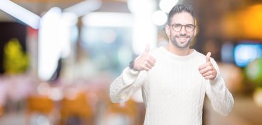 Yakışıklı delikanlı izole arka plan başarı işareti el ile pozitif jest yapıyor üzerinde gözlük takan başparmak gülümseyen ve mutlu. Neşeli bir ifadeyle, kazanan jest kameraya bakıyor.