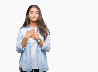 Eller genç güzel Arap kadın ile gülümseyen izole arka plan üzerinde kapalı gözler ve yüzünde minnettar jest ile göğüs üzerinde. Sağlık kavramı.