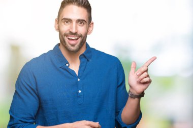 Kameraya bakarak yan el ve parmak ile işaret eden genç yakışıklı adam yüzünde kocaman bir gülümseme ile izole arka plan üzerinde.