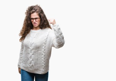 Öfkeli ve sinirli sinirli ve öfke ile bağırarak süre öfkeli yumruk yükselterek izole arka plan üzerinde güzel esmer kıvırcık saçlı Genç kız giyiyor kış kazak. Öfke ve agresif kavramı.