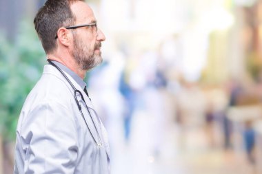 Tıbbi üniforma izole arka tarafına, seyir giyen orta yaş üst düzey ağarmış Doktor adam sakin ol kendine güvenen gülümseme ile doğal yüz pozuyla profili.