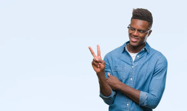 年轻的非洲裔美国人在孤独的背景微笑着愉快的脸眨眨眼在相机做胜利标志 第二个 — 图库照片