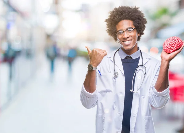 Afro american neurologist doctor or psychology man over isolated background pointing and showing with thumb up to the side with happy face smiling