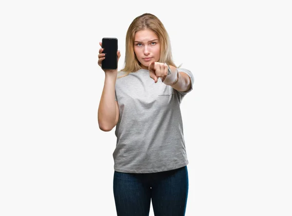 年轻的白种人妇女显示屏幕的智能手机在孤立的背景指向相机和你 正面和自信的手势从前面 — 图库照片