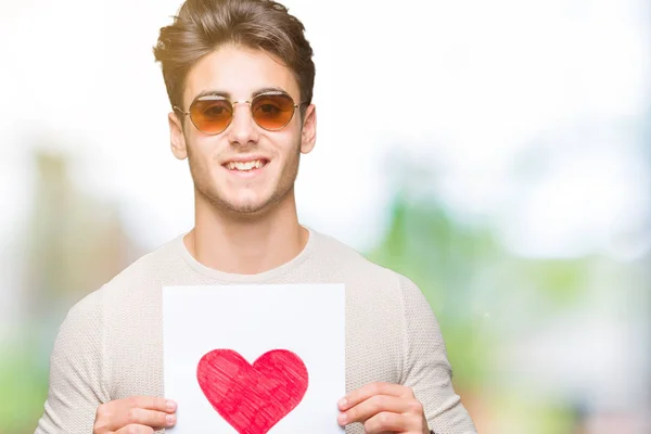 Joven Hombre Guapo Sosteniendo Tarjeta Con Corazón Rojo Sobre Fondo — Foto de Stock