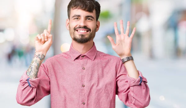 Gösterilen ve parmakları ile işaret izole arka plan üzerinde pembe gömlek giymiş genç yakışıklı adam kendinden emin ve mutlu gülümseyerek süre 6 numara.