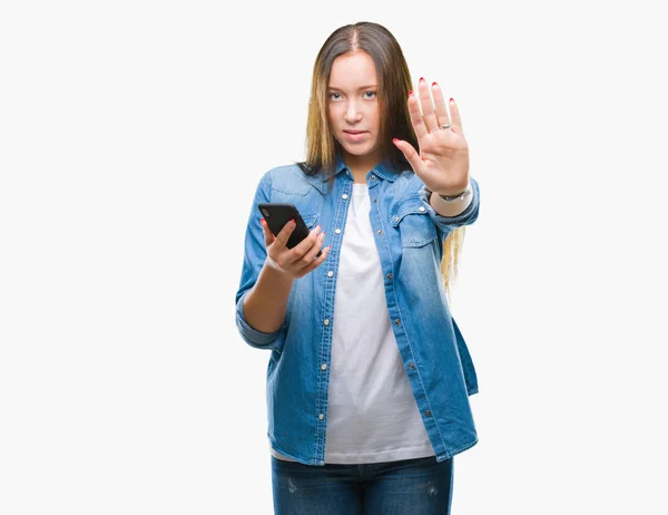 年轻美丽的高加索妇女发短信发送消息使用智能手机在孤立的背景与开放的手做停止标志与严肃和自信的表达 防御姿态 — 图库照片