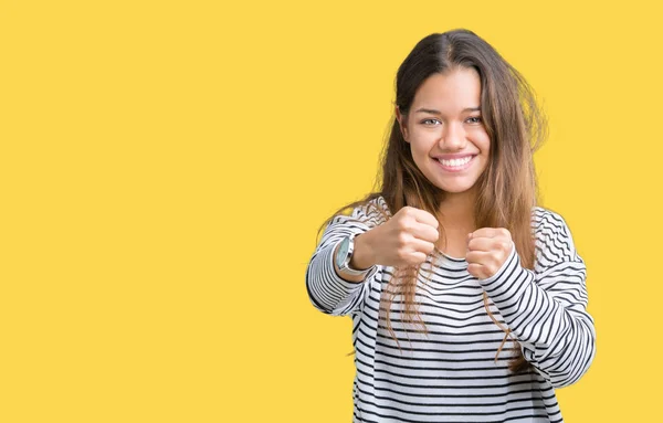 Young beautiful brunette woman wearing stripes sweater over isolated background Ready to fight with fist defense gesture, angry and upset face, afraid of problem