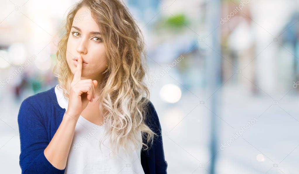 Beautiful young blonde woman over isolated background asking to be quiet with finger on lips. Silence and secret concept.
