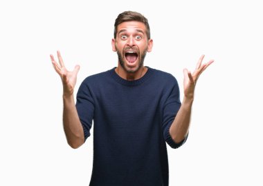 Üzerinde kış kazak giyen genç yakışıklı adam deli kutluyor arka plan izole ve başarı için kaldırdı kollarını açarak hayrete ve heyecanlı çığlık gözleri açık. Kazanan kavramı