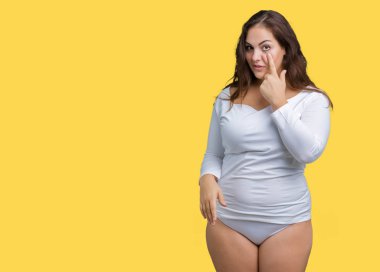 Artı boyutu genç overwight kadın güzel beyaz iç çamaşırı üzerinde izole giyiyor arka plan işaret jest göz izlemek için şüpheli ifade