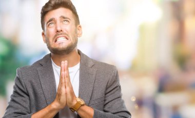 Genç yakışıklı iş adamı yalvarıyor ve umut ifade yüzünde çok duygusal ve endişe ile birlikte elleriyle dua izole arka plan üzerinde. Bağışlanmak. Din kavramı.