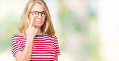 Güzel genç kadın gözlük izole üzerinde arka plan işaret jest göz izlemek için şüpheli ifade