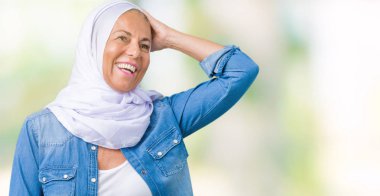 El hareketi ile kendine güvenen dokunaklı saç gülümseyerek, çekici poz izole arka plan üzerinde Arap hijab giyen orta yaş Doğu Arap kadın
