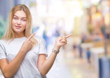 Gülümseyen ve iki elleri ve parmakları ile tarafına işaret kamera bakarak izole arka plan üzerinde beyaz kadın.