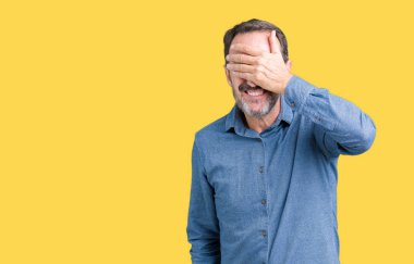 Yakışıklı orta yaş gülümsüyor ve gözleri için sürpriz kapsayan yüz el ile gülüyor izole arka plan üzerinde zarif komuta sizde. Kör kavramı.