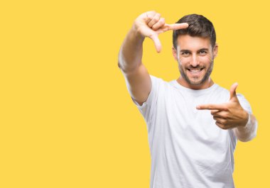 Yakışıklı delikanlı elle yapma çerçeve ve parmakları ile mutlu yüz gülümseyen izole arka plan üzerinde. Yaratıcılık ve Fotoğrafçılık kavramı.