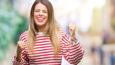 Genç güzel kadın rahat çizgili kış kazak üzerinde izole arka plan çok mutlu ve heyecanlı gülümseyen ve başarı için çığlık kaldırdı, silah ile kazanan jest yapıyor. Kutlama kavramı.