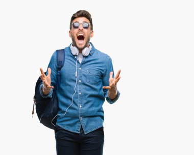 Üzerinde kulaklık ve sırt çantası giyen genç yakışıklı turist adam arka plan deli izole ve deli bağırarak ve agresif ifade ve silah kaldırdı bağırıyor. Hayal kırıklığı kavramı.