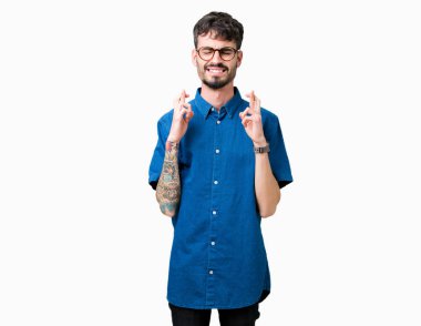 Umut ve gözleri kapalı geçiş parmaklarıyla gülümseyen izole arka plan üzerinde gözlük takan yakışıklı delikanlı. Şans ve batıl kavramı.