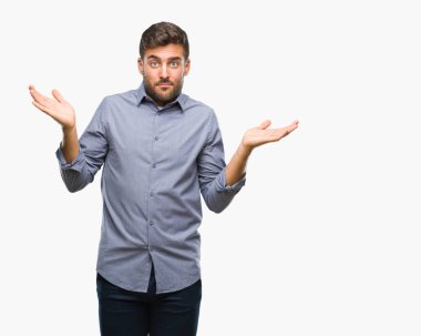 İzole arka plan clueless ve şaşkın bir ifadeyle kollar ve eller kaldırdı genç yakışıklı adam. Şüphe kavramı.