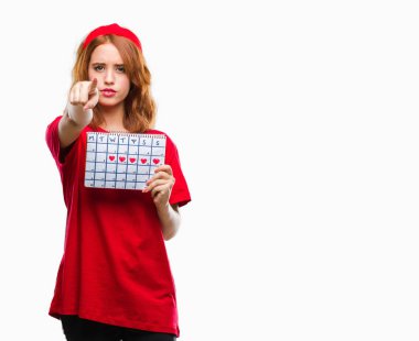 Genç güzel kadın adet takvim kamera ve size parmak ile işaret tutan izole arka plan üzerinde el işareti, pozitif ve kendinden emin bir jest ön