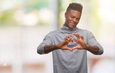 Afrikalı-Amerikalı genç aşık kalp simgesi ve elleriyle şekil gösteren gülümseyen izole arka plan üzerinde. Romantik kavramı.