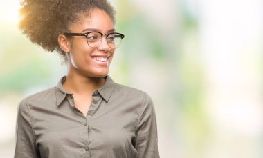 Uzak tarafına yüzünde, doğal ifade gülümseme ile seyir izole arka plan üzerinde gözlük takan genç afro Amerikalı kadın. Kendine güvenen gülüyor.