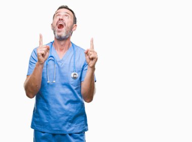 Orta yaş ağarmış kıdemli Doktor adam izole arka plan üzerinde tıbbi üniforma hayret ve yukarıya bakıp parmakları ile işaret şaşırttı ve silah kaldırdı.