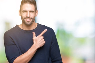 İzole arka neşeli bir gülümseme ile el ve parmak kadar yan yüzünde mutlu ve doğal ifade ile işaret yüz üzerinden kazak giyen genç yakışıklı adam