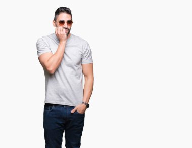 Genç yakışıklı adam stresli ve gergin ile izole arka plan üzerinde güneş gözlüğü takıyor tırnak ısırma dudaklarından eller. Anksiyete sorunu.