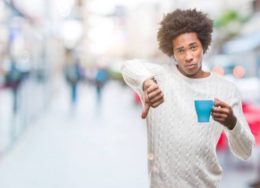 Kızgın yüz, eksi işareti aşağı antipati başparmak ile gösterilen, ret kavramı ile izole arka plan üzerinde kahve içme Afro Amerikalı adam