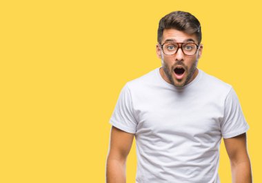 Korkuyor ve şok sürpriz ifade, korku ve heyecan yüz ile izole arka plan üzerinde gözlük takan genç yakışıklı adam.