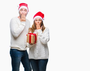 Orta yaş İspanyol çift, Noel şapka ve holding hediye izole arka kapak ağız elle hata için utanç ile şok üzerinde giyen ifade korku korkuyor sessizlik içinde gizli kavramı