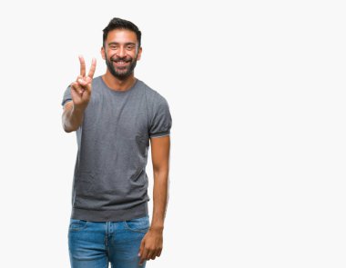 Mutlu yüz zafer işareti yaparken kameraya göz kırpıyor ile gülümseyen izole arka plan yetişkin İspanyol adam. İki numaralı.
