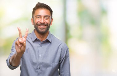 Mutlu yüz zafer işareti yaparken kameraya göz kırpıyor ile gülümseyen izole arka plan yetişkin İspanyol adam. İki numaralı.