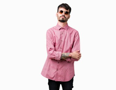 Genç yakışıklı adam izole arka plan şüpheci ve sinir, onaylamayan ifade yüz çapraz kolları üzerinde güneş gözlüğü takıyor. Negatif kişi.